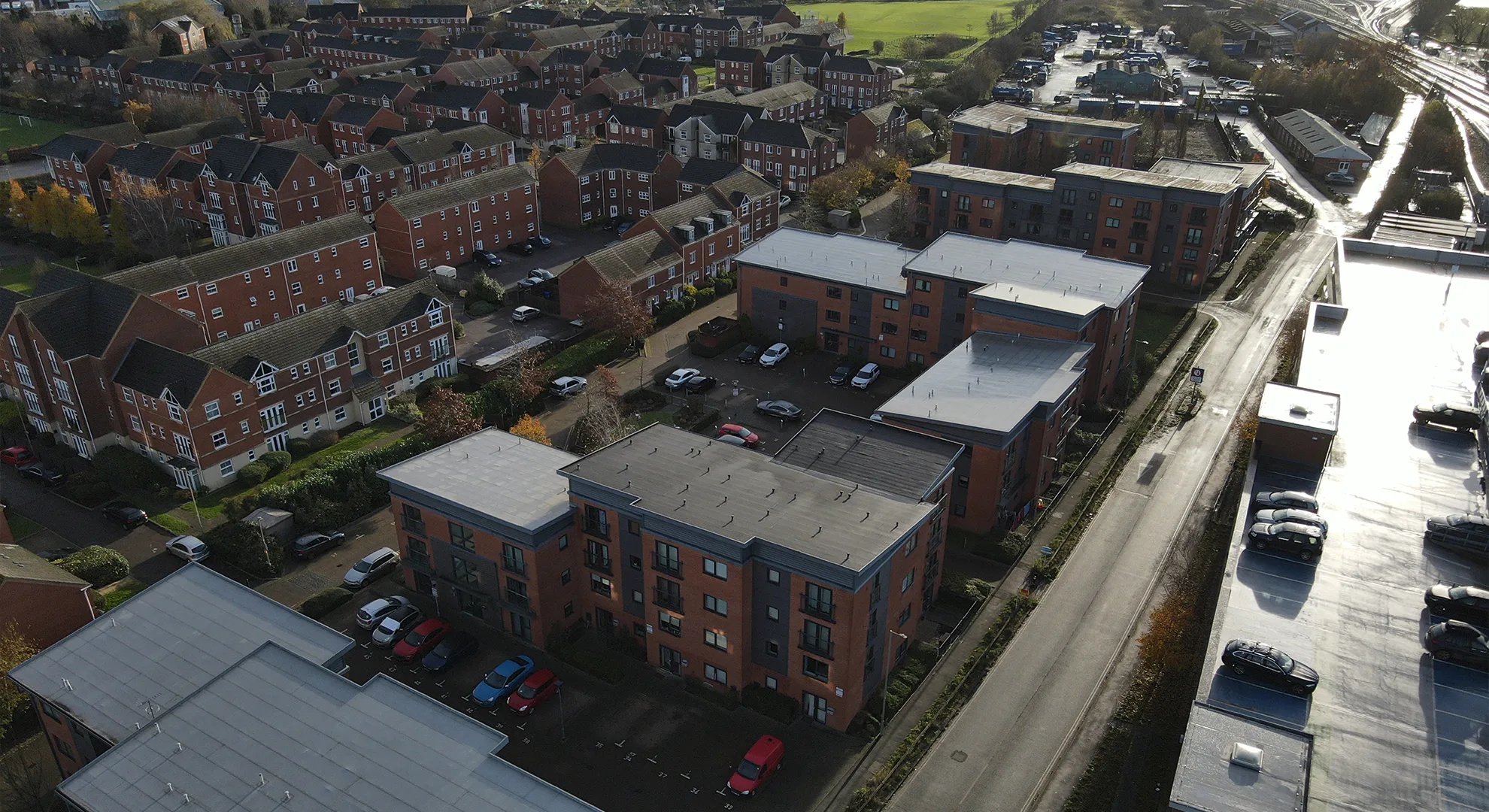 Aerial drone view looking down at modern flat-roofed apartment buildings and surrounding residential housing.