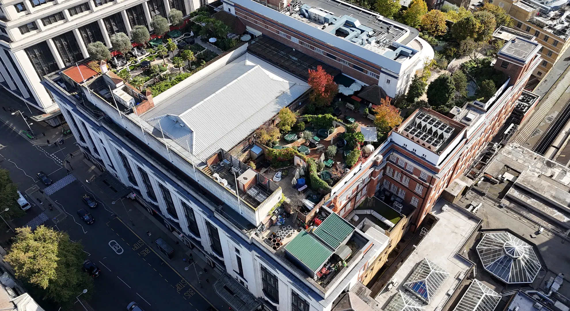 Drone aerial view of a large building with a lush rooftop garden featuring trees, paths, and seating areas