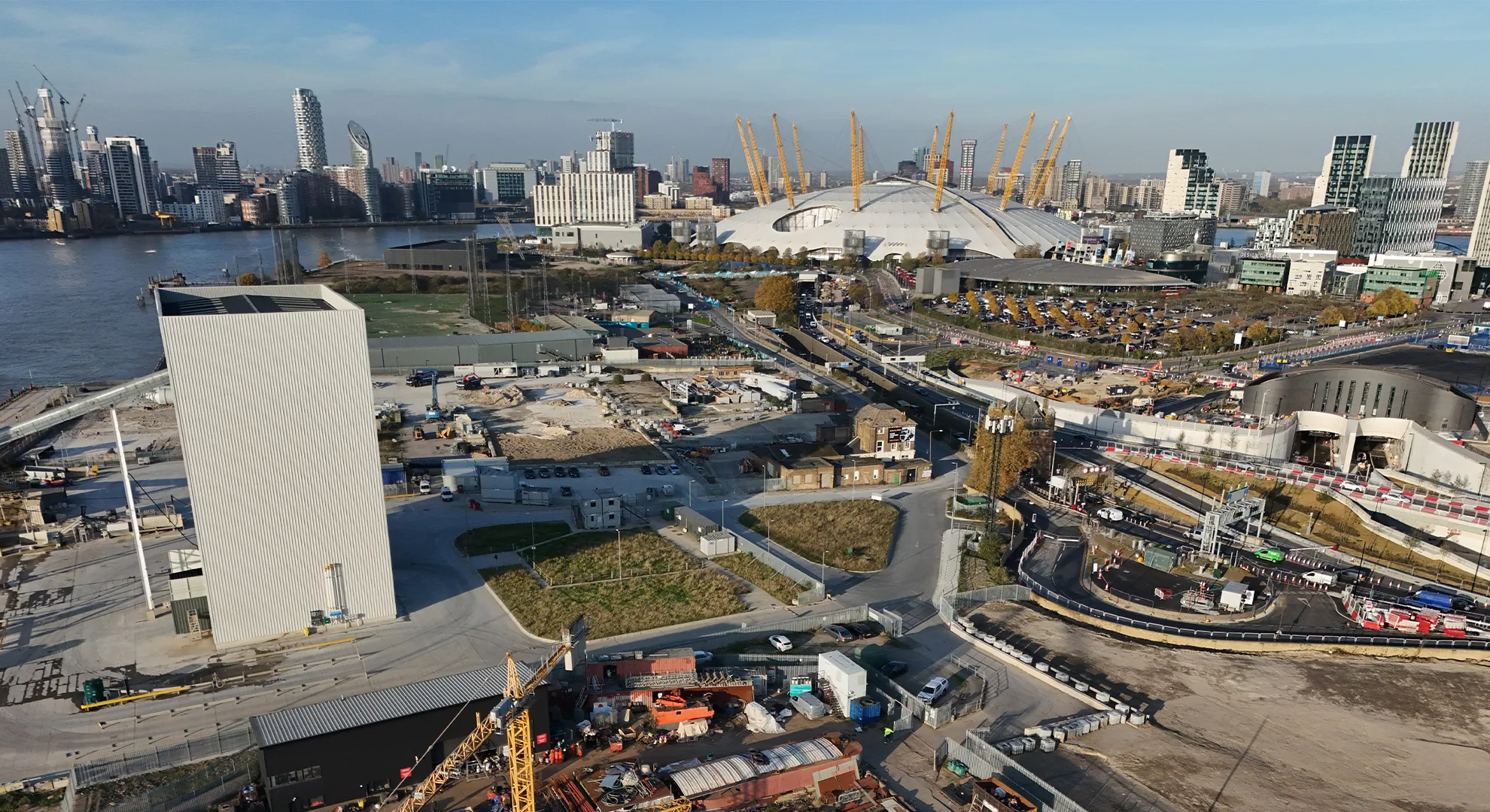 Aerial view via drone of the Greenwich Peninsula in London, featuring the O2 Arena, construction sites, and the River Thames