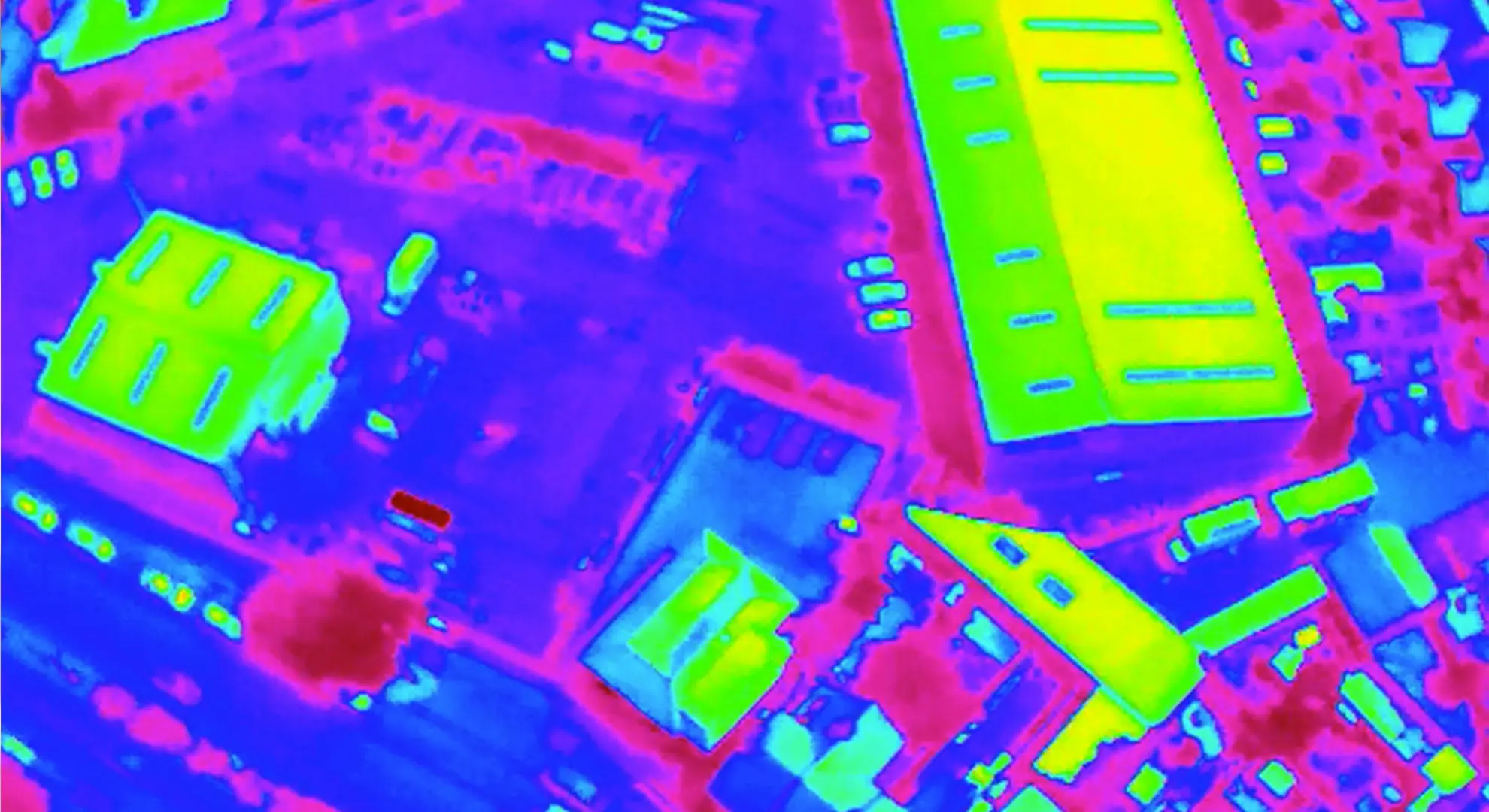 Aerial thermal image showing heat signatures of buildings in bright green and yellow