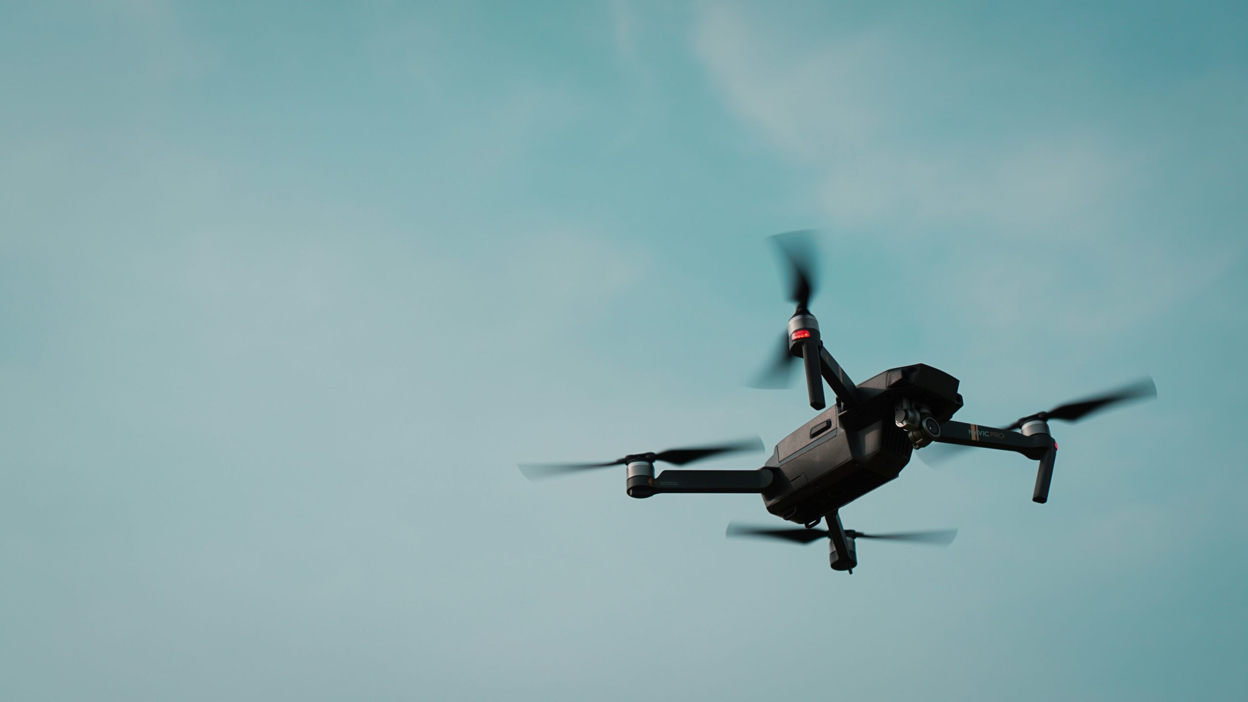 Quadcopter survey drone flying against a blue-green sky