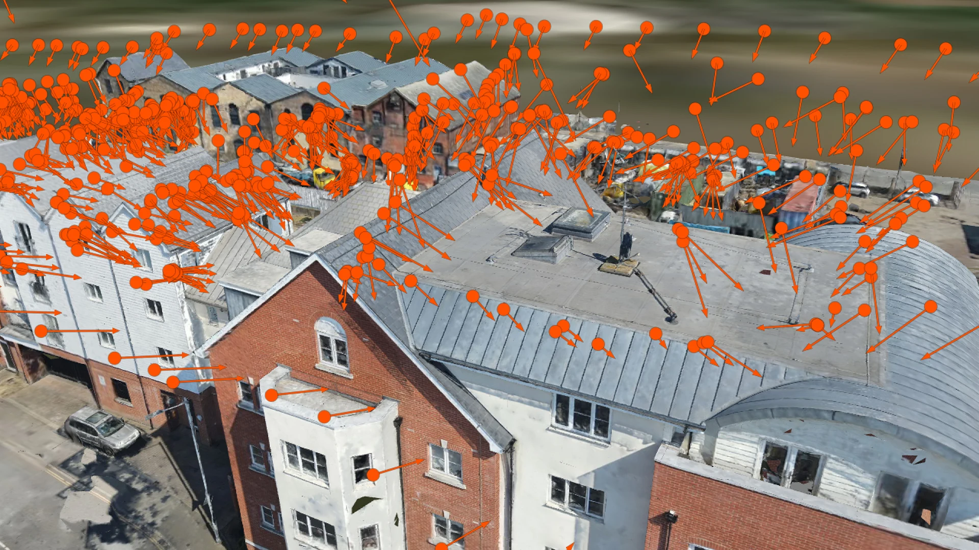 3D photogrammetry model of building rooftops and facades overlaid with orange camera position markers from an aerial drone survey.
